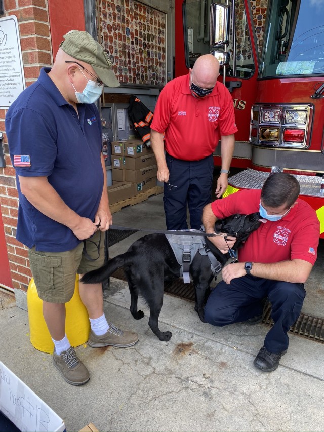 Charles Ellis (left), a Clear Path for Veterans New England volunteer introduces service dog Harry to Devens Fire Departement Cpt. Michael Whitter (right) r and Figherfighter Todd Whitter (middle) in Devens Mass. Sept. 11. 2020. Service dog training is one of many services that Clear Path for Veterans New England offers to veterans in need. The non-profit organization visited the fire department to donate supplies to in honor of 9/11 and first responders. (U.S Army Photo taken by Spc. Christie Ann Belfort.)