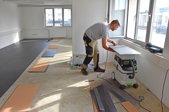 WIESBADEN, Germany - An employee from the U.S. Army Garrison Wiesbaden Directorate of Public Works installs vinyl flooring in a day room in barracks building 1206 Aug. 27 on Clay Kaserne. Day rooms provide a space for recreation and unwinding.