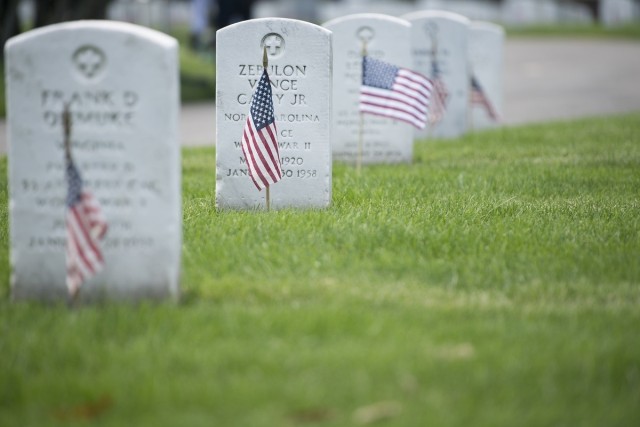 American flags stand in front of headstones in Section 17 of Arlington National Cemetery during Flags-In, May 26, 2016, in Arlington, Va. 