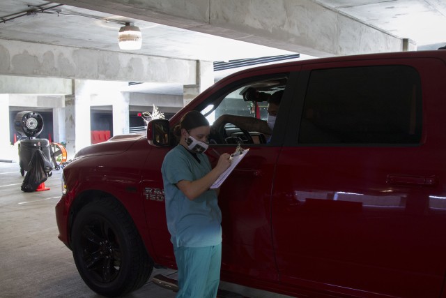 Spc. Sara Jackson, 502nd Dental Company Area Support, takes a patients information as they enter the drive-thru Aug. 18.  The 61st Multifunctional Medical Battalion, 1st Med. Bde., have led efforts at CRDAMC’s COVID-19 testing drive-thru site inside the hospital’s garage since June 29.  (U.S. Army photo by Sgt. 1st Class Kelvin Ringold)