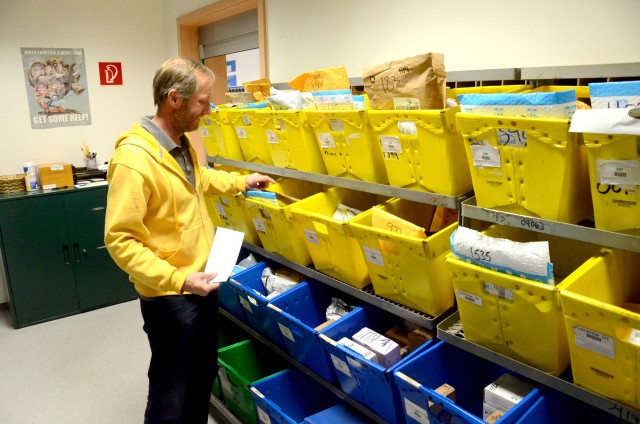 David Chinchen, USAG Rheinland-Pfalz Rhine Ordnance Barracks postal service employee, checks the small packages boxes for a customer's mail at the ROB Postal Services Center package pickup window.
