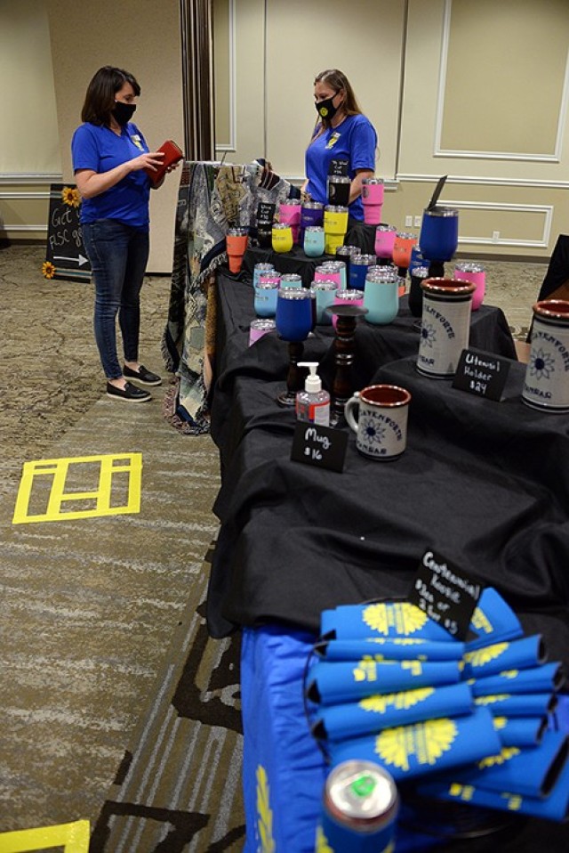 Lauren Bolen, Fort Leavenworth Spouses Club adviser, pays for her purchase of FLSC memorabilia with Shawlyn Dungan, FLSC ways and means co-chairperson, during the FLSC Super Sign-up Sept. 9 at the Frontier Conference Center. FLSC centennial...