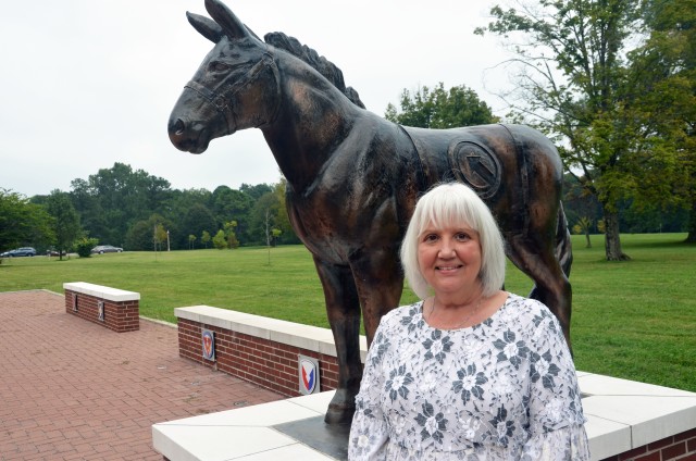 Barbara Wright, assistant to the command group, Special Troops Battalion, 1st Theater Sustainment Command, stands next to the statue of Blackjack outside of Fowler Hall where she works at Fort Knox, Kentucky, Sept. 10, 2020. She is responsible for ensuring  daily operations within the battalion under the two-star command run smoothly by scheduling events and meetings, allowing the STB commander, executive officer, and senior enlisted advisor, freedom to focus their attention on the mission. (U.S. Army photo by Spc. Kaylee Harris, 1st TSC Public Affairs)