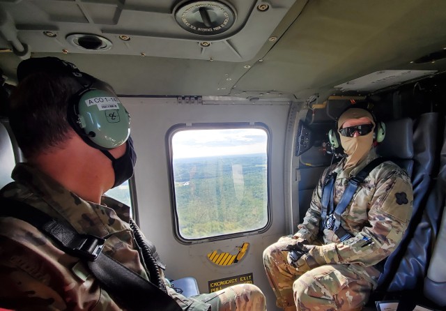 Col. Michael D. Poss, Fort McCoy Garrison commander, and Brig. Gen. John C. Hafley, 88th Readiness Division deputy commanding general participate in a familiarization flight Aug. 4, 2020, on board a Wisconsin National Guard UH-60 Black Hawk helicopter over Fort McCoy, Wis. Several Army leaders participated in the flight where they learned more about the training areas of the installation and observed troops training in the field. (U.S. Army Photo by Scott T. Sturkol, Public Affairs Office, Fort McCoy, Wis.)