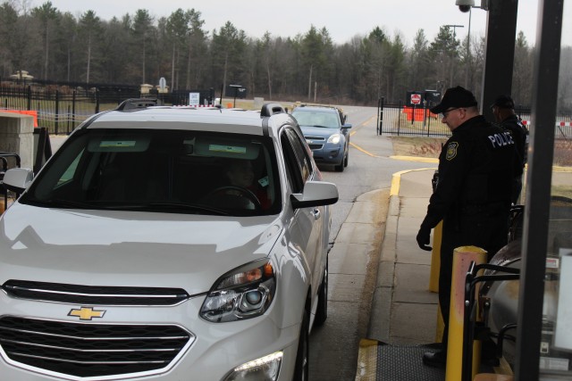 Officer Mark Johnson with the Directorate of Emergency Services Police Department reviews a motorist’s ID and asks screening questions April 3, 2020, at the Main Gate entry control point at Fort McCoy, Wis. Fort McCoy police have limited entry...