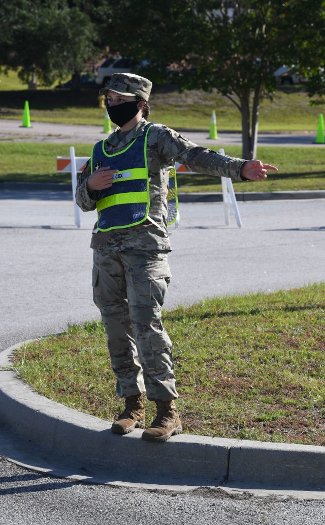 Spc. Asthon Cox, an orderly room clerks, with Company B, Headquarters and Headquarters Battalion, directs motorists to their testing areaduring drive thru COVID-19 testing at Fort Jackson Sept. 22.