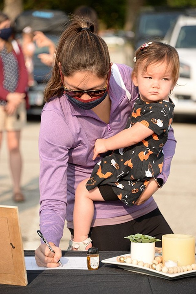 Emily Bonilla, with 1-year-old Maddie, registers for Women of St. Ignatius at the WOSI/Catholic Women of the Chapel kick-off event Sept. 17 outside Frontier Chapel. A kick-off message was broadcast live via Facebook for viewers to watch from the parking lot or home, then they could register and pick up their welcome bags outside the chapel. Photo by Prudence Siebert/Fort Leavenworth Lamp