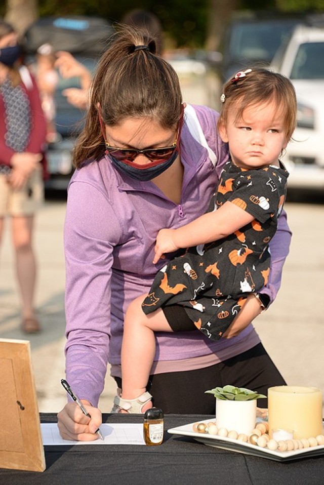 Emily Bonilla, with 1-year-old Maddie, registers for Women of St. Ignatius at the WOSI/Catholic Women of the Chapel kick-off event Sept. 17 outside Frontier Chapel. A kick-off message was broadcast live via Facebook for viewers to watch from the...