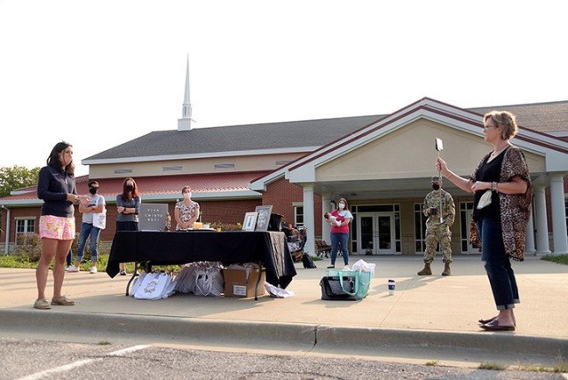 Next to a table of welcome bags, Maggie Phillips, Women of St. Ignatius president, welcomes viewers to the WOSI kick-off event, being broadcast via Facebook Live by Michelle Taylor, Catholic community coordinator, during the WOSI/Catholic Women of...