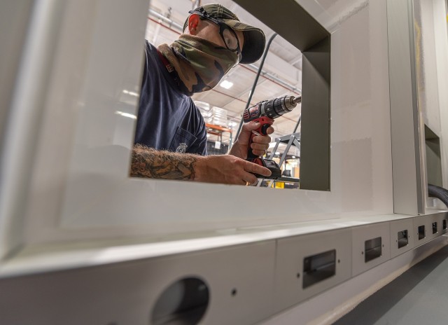 Sheet Metal Mechanic Kenny Laytos cores the exterior of a Base Defense Operations Center shelter.