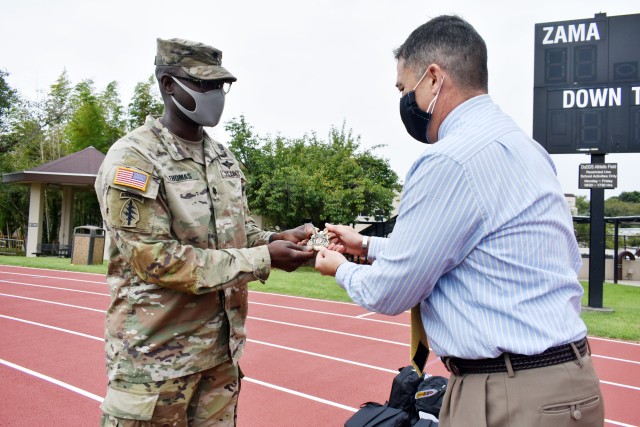 Lt. Col. Demetrick Thomas, left, commander of the 35th Combat Sustainment Support Battalion, presents Henry LeFebre, principal of Zama Middle High School, a battalion coin at the school, Camp Zama, Japan, Sept. 24. The battalion has an...