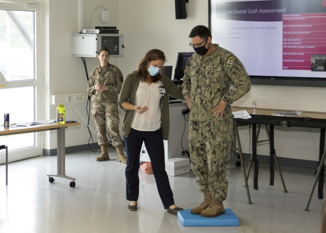 Katherine Perlberg, a physical therapist at Landstuhl Regional Medical Center’s Traumatic Brain Injury Clinic, performs a balancing test on Petty Officer 2nd Class, John Toomer, a hospital corpsman from Naval Hospital Naples, during Landstuhl Regional Medical Center’s Virtual Health Presenters Course, Sept. 3. The course enables health care staff to conduct patient presentations for providers via virtual health capabilities. (U.S. Army photo by Clay Beach)