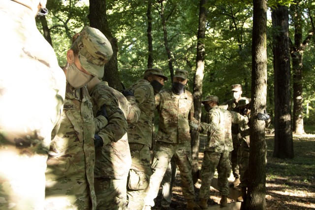 Officer Candidate School candidates of class 65 link arm to arm for stability as they navigate through a balance beam obstacle at the Webster Conference Center in Salina, Kansas, September 13, 2020. “You can’t do it alone,” said Zachary...