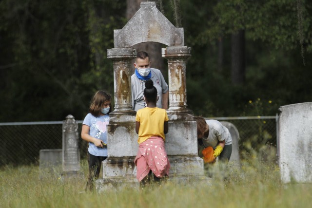 Brian Greer, an archaeologist with Directorate of Public Works, Environmental Division, Prevention and Compliance Branch, Cultural Resource Management, and children of Fort Stewart schools work to clean headstones Sept. 25 at Taylors Creek...