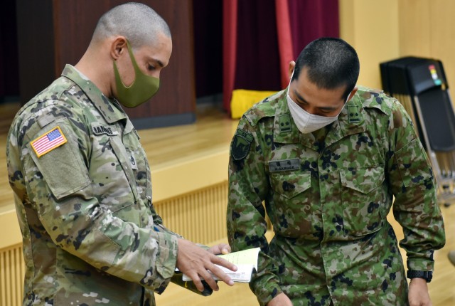 Staff Sgt. James Hankins, left, individual mobilization augmentee manager for U.S. Army Reserve Affairs Japan, U.S. Army Japan, speaks with 1st Lt. Akito Saruge, a member of the Japan Ground Self-Defense Force, during an exercise included in the...