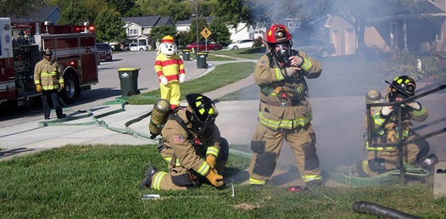 Fort Leavenworth Fire and Emergency Services firefighters Terrance Carr, Dylan Honeycutt, Capt. Richard Baggett and Melissa Tull, joined by Sparky the Fire Dog, portrayed by Fire Inspector Antonio Masisak, respond to a mock kitchen fire call...