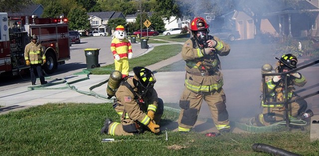 Fort Leavenworth Fire and Emergency Services firefighters Terrance Carr, Dylan Honeycutt, Capt. Richard Baggett and Melissa Tull, joined by Sparky the Fire Dog, portrayed by Fire Inspector Antonio Masisak, respond to a mock kitchen fire call during the making of a Fire Prevention Week video Sept. 25 off Hunt Loop. "Serve up fire safety in the kitchen" is the theme of this year's Fire Prevention Week. Photo by Prudence Siebert/Fort Leavenworth Lamp