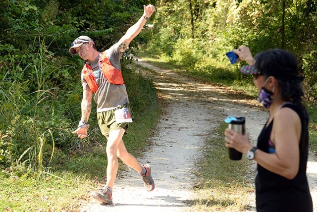 Race participant Mark Kramer rounds a turn along the 1908 Ultra Challenge trail run route as event organizer Col. Angel Liberg, Combined Arms Center Army Reserve Affairs assistant chief of staff, rattles a cowbell near completion of the first...