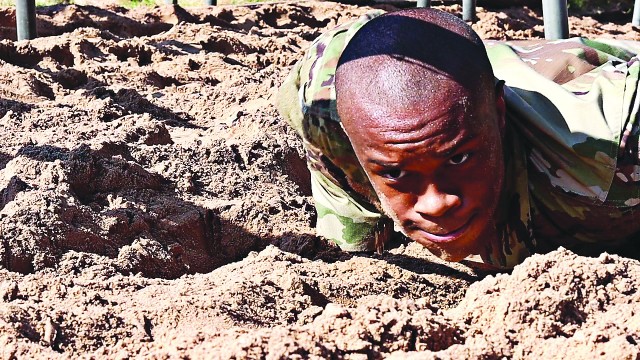 Face first, a Basic Combat trainee low crawls under barbed wire before heading to the next obstacle in the Combat Conditioning Course.