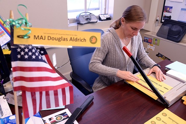 Retired 1st Sgt. Jennifer Douglas, Survivor Outreach Services coordinator, cuts strips of yellow paper, printed with the names of the nearly 400 area fallen service members, as she prepares for the Run/Walk for the Fallen Sept. 28 in her office at...