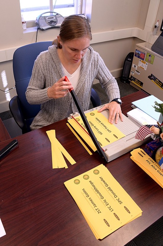 Retired 1st Sgt. Jennifer Douglas, Survivor Outreach Services coordinator, cuts strips of yellow paper, printed with the names of the nearly 400 area fallen service members, as she prepares for the Run/Walk for the Fallen Sept. 28 in her office at...