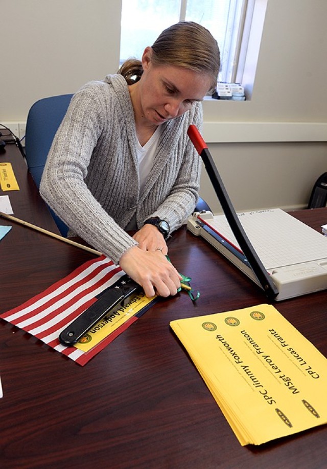 Retired 1st Sgt. Jennifer Douglas, Survivor Outreach Services coordinator, staples a strip of yellow paper, printed with one of the nearly 400 names of area fallen service members, to a flag as she prepares the flags for the Run/Walk for the...