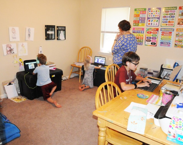 Catherine Withee stands with her children Tyson, 7, (left) Lillianna, 5, (middle) and Jacob, 11, as they do schoolwork.