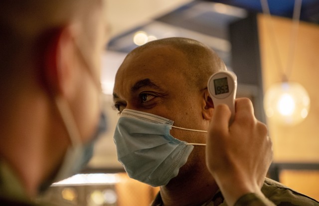 Col. Brandon J. Pretlow, commander of the 531st Hospital Center, gets his temperature checked by Spc. Nicholas Digrado, assigned to the 501st Area Support Medical Company, at a local hotel’s health checkpoint in New York City, May 30, 2020. Military medical personnel assigned to the hospital collaborate as an integrated system in support of New York City&#39;s medical system, as part of the Department of Defense COVID-19 response. 