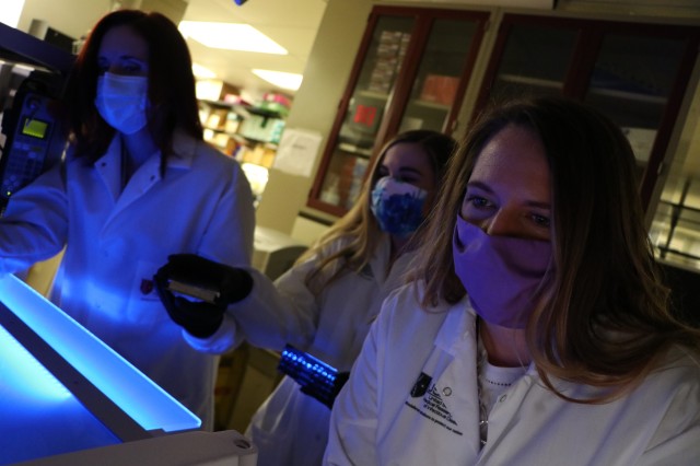 U.S. Army Medical Research Institute of Infectious Diseases researchers Laura Prugar (blue mask), Kathleen Huie (print mask) and Nicole Josleyn
(purple mask) use a microneutralization assay and a high-throughput fluorescent imaging system to determine levels of neutralizing antibody to SARS-CoV-2 in convalescent patients. (John W. Braun Jr., USAMRIID VIO)