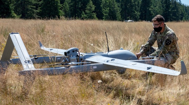 Spc. Gunner Livingston, an unmanned aircraft repairer, 1-2 Stryker Brigade Combat Team, 7th Infantry, inspects the Aerosonde Hybrid Quad before a vertical take off at a training site at Joint Base Lewis-McChord, Wash., June 21-22. The Aerosonde HQ...
