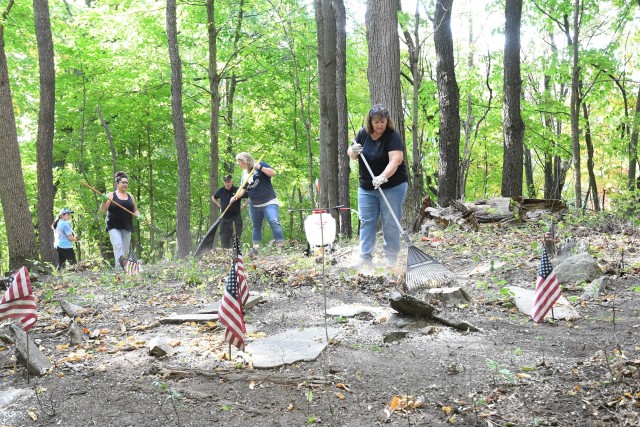 Members of LEADER Class VII join Dr. Laurie Rush, Fort Drum Cultural Resources manager, (left) at the John Betts / War of 1812 Cemetery in the town of Denmark in September. The group removed debris from the cemetery and cleared markers and headstones that were half-hidden or covered. They also cleaned the headstones and then mapped the cemetery. This was a class DEO, or developmental experience opportunity, which is a requirement in the Leader Enhancement and Developmental Education Requirements (LEADER) program. (Photo by Mike Strasser, Fort Drum Garrison Public Affairs)