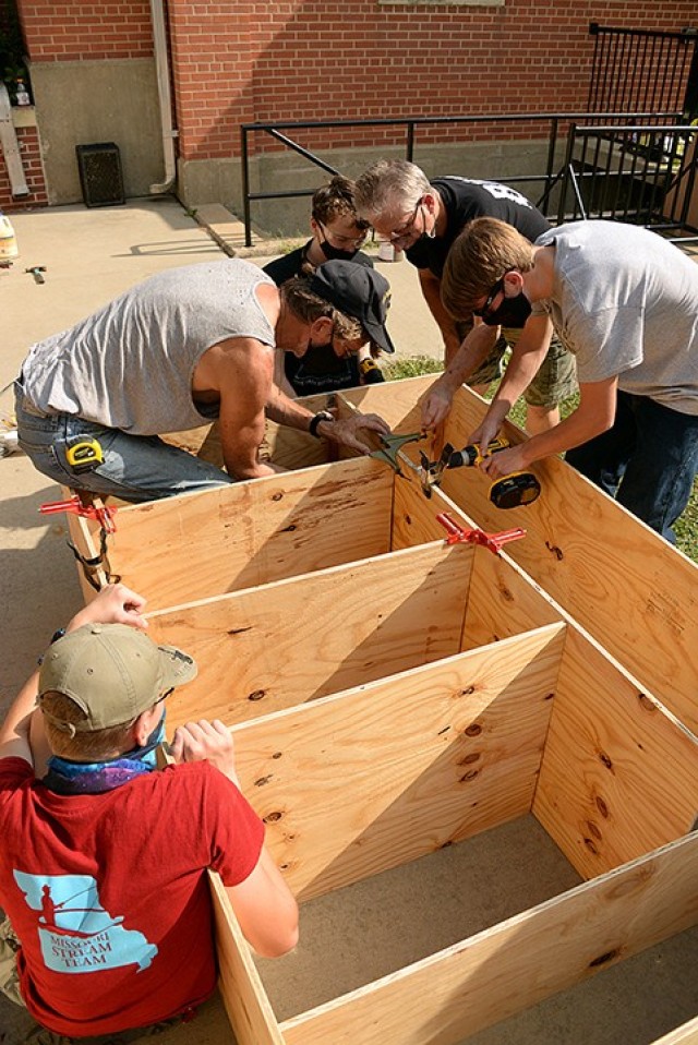 Scouts BSA Troop 366 member Aiden Harris holds a board in place as adult volunteer Darryl Ragsdale, Troop 165 member John Goodman, adult volunteer Mark Burton and Troop 366 member Arlin Groefsema work on another section of a blessing box, Troop...