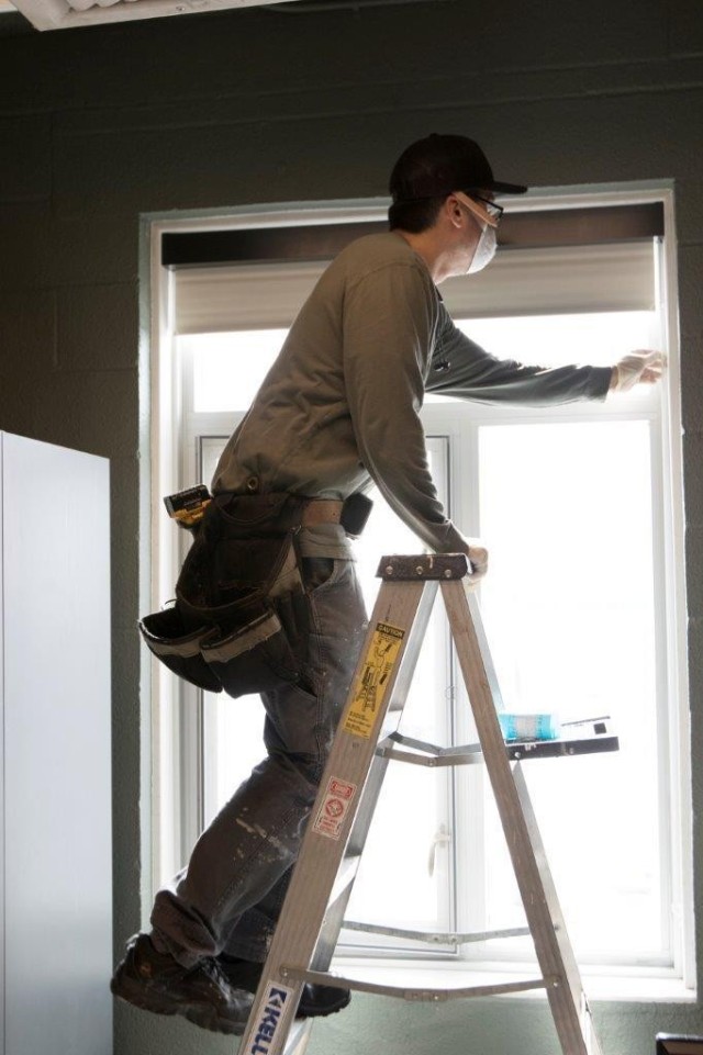 A worker installs a blackout shade in a barrack on Fort Wainwright in March 2020. To install the blinds during COVID-19, crews wore masks and gloves with cleaning crews coming before and after their work to ensure that the Soldiers would not be...