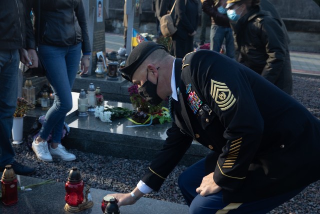 Command Sgt. Maj. Douglas Danielson lays a candle votive on the grave of a fallen soldier during a Defender’s Day memorial ceremony at the historical Lychakiv Cemetery in Lviv, Ukraine, Oct. 14. (Photo by U.S. Army Cpl. Shaylin Quaid, JMTG-U...