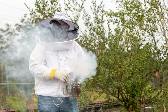 Environmental Protection Specialist Sean Maynard gets the smoker ready to sedate the honey bees prior to opening the hive.