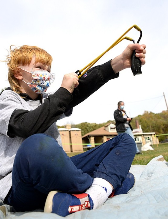 After loading a slingshot with a dry bean, 8-year-old Abel Rolf takes aim to try to hit a hanging pie tin during the Cub Scout Pack 1 Shooting Sports Day Oct. 17 at Hunt Lodge. Photo by Prudence Siebert/Fort Leavenworth Lamp