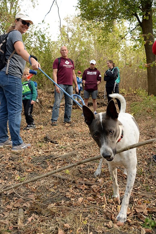 Military Wild member Beth Watt's Mexican hairless dog Harvey carries around a large stick as trail guide Natural Resource Specialist Neil Bass tells hikers about possible snakes in the area during a 2.5-mile hike Oct. 17 by Sherman Army Airfield....