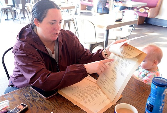Fort Leavenworth Spouses' Club Historian Emily Hetherington, with her 7-month-old daughter Madison, looks at some FLSC-related memorabilia, including a new member welcome letter from 1960, while talking about the club's 100-year history Oct. 16 at...