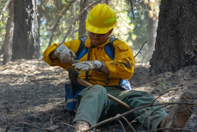 Spc. Bailey Walker with the 14th Brigade Engineer Battalion, from Joint Base Lewis-McChord, Washington, sharpens his Pulaski after mopup operations in Mendocino National Forest, Nothern California, Friday, Sept. 4, 2020. The Pulaski, a special...