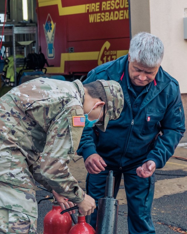 WIESBADEN, Germany - - Thilo Schleich, fire prevention inspector for the Directorate of Emergency Services, watches as Pfc. Jose Rivas Morales, Strong Europe Café dining facility, remove the safety pin of a fire extinguisher in preparation for...