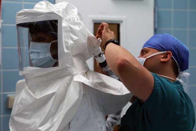 Maj. (Dr.) Neel Shah, an anesthesiologist at Landstuhl Regional Medical Center, gets assistance with putting on a powered air-purifying respirator.