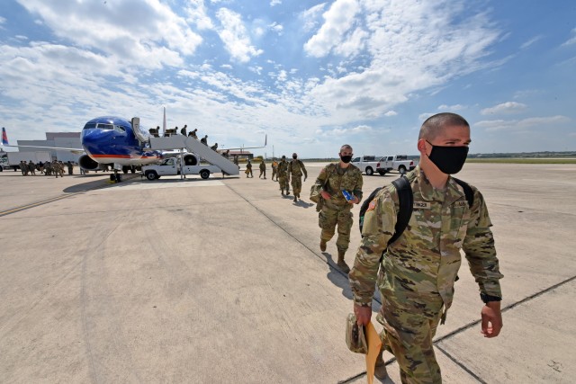 Soldiers walk to a hangar at Kelly Field, San Antonio after arriving on a chartered flight from Fort Jackson.