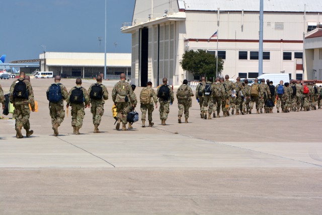 Soldiers walk to a hangar at Kelly Field, San Antonio after arriving on a chartered flight from Fort Jackson.