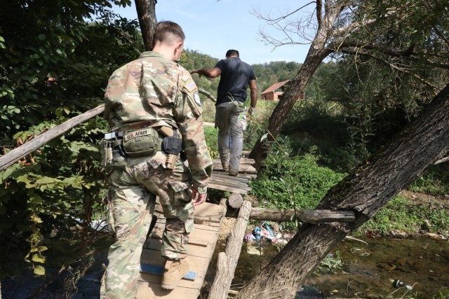 STREZOVCE/STREZOFC, Kosovo--- KFOR Regional Command East Soldiers follow a local subsistence farmer on a half-mile trek the village water source and brace themselves as they cross a narrow rickety foot bridge made of wooden planks and clutch the...
