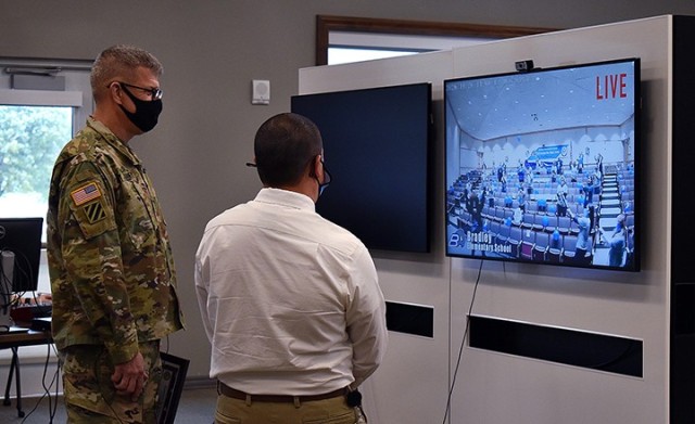 Lt. Gen. James Rainey, Combined Arms Center and Fort Leavenworth commanding general, and Michael Burrow, Bradley Elementary School principal, watch the live stream to Bradley auditorium as staff and faculty celebrate with party poppers and...