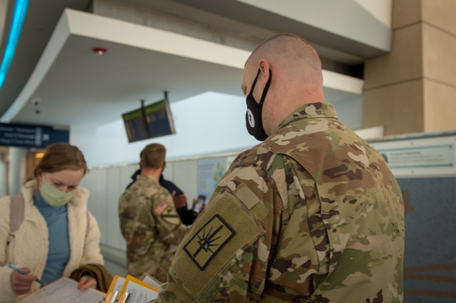 Army Staff Sgt. James Kociencki, Soldier assigned to 105th Military Police Company, Buffalo, N.Y., greets an inbound passenger during flight arrivals at Buffalo-Niagara International Airport, supporting the state’s travel advisory Oct. 23, 2020....