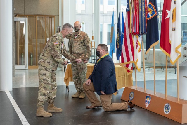 John Dougherty, test officer at the U.S. Army Aberdeen Test Center (ATC) (right), is ceremoniously knighted in to the Order of Saint George with receipt of the Noble Patron of Armor Award Oct. 22 in a ceremony at U.S. Army Test and Evaluation Command (ATEC). ATEC Commanding General Brig. Gen. James Gallivan (left) and ATEC Command Sergeant Major, Command Sgt. Maj. Ronald Graves presented the U.S. Army award, which honors exceptional supporters of the morale and welfare of the soldiers of Armor and Cavalry units and organizations. 