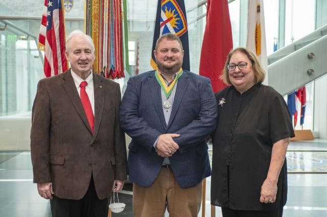 John Dougherty, test officer at the U.S. Army Aberdeen Test Center (ATC) (center), is pictured with his parents, Steve Dougherty (left) and Cyndy Dougherty (right). Dougherty was accepted into the Order of Saint George with receipt of the Noble Patron of Armor Award in a ceremony on Oct. 22 at the U.S. Army Test and Evaluation Command (ATEC). The U.S. Army award honors exceptional supporters of the morale and welfare of the soldiers of Armor and Cavalry units and organizations.  