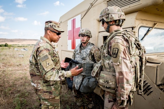 Then-Army Brig. Gen. Clement S. Coward talks to Sgt. Gregory A. Smith and Spc. Michael L. Haddon during field training at Fort Sill, Okla., Sept. 12, 2019. Coward inquired about the types of injuries the medics had seen most frequently during the field training.