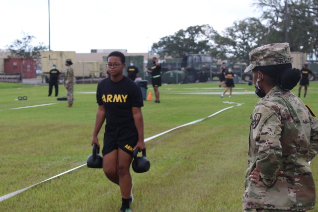 Pvt. Trinity Beckford carries two 40-pound kettle bells as part of the Army Combat Fitness Test as Sgt. Latiria Stewart observes during training on the ACFT in Belle Chasse, Louisiana Oct. 25, 2020.  Soldiers took extra COVID safety precautions as they trained on the ACFT during the 377th Theater Sustainment Command battle assembly. 